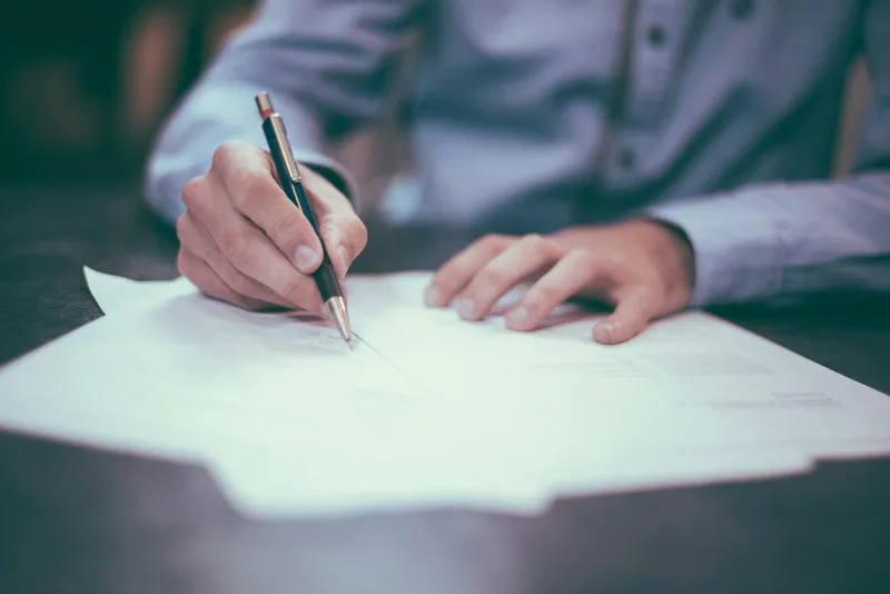 Documenti e penna su una scrivania professionale — il lavoro invisibile dietro ogni selezione